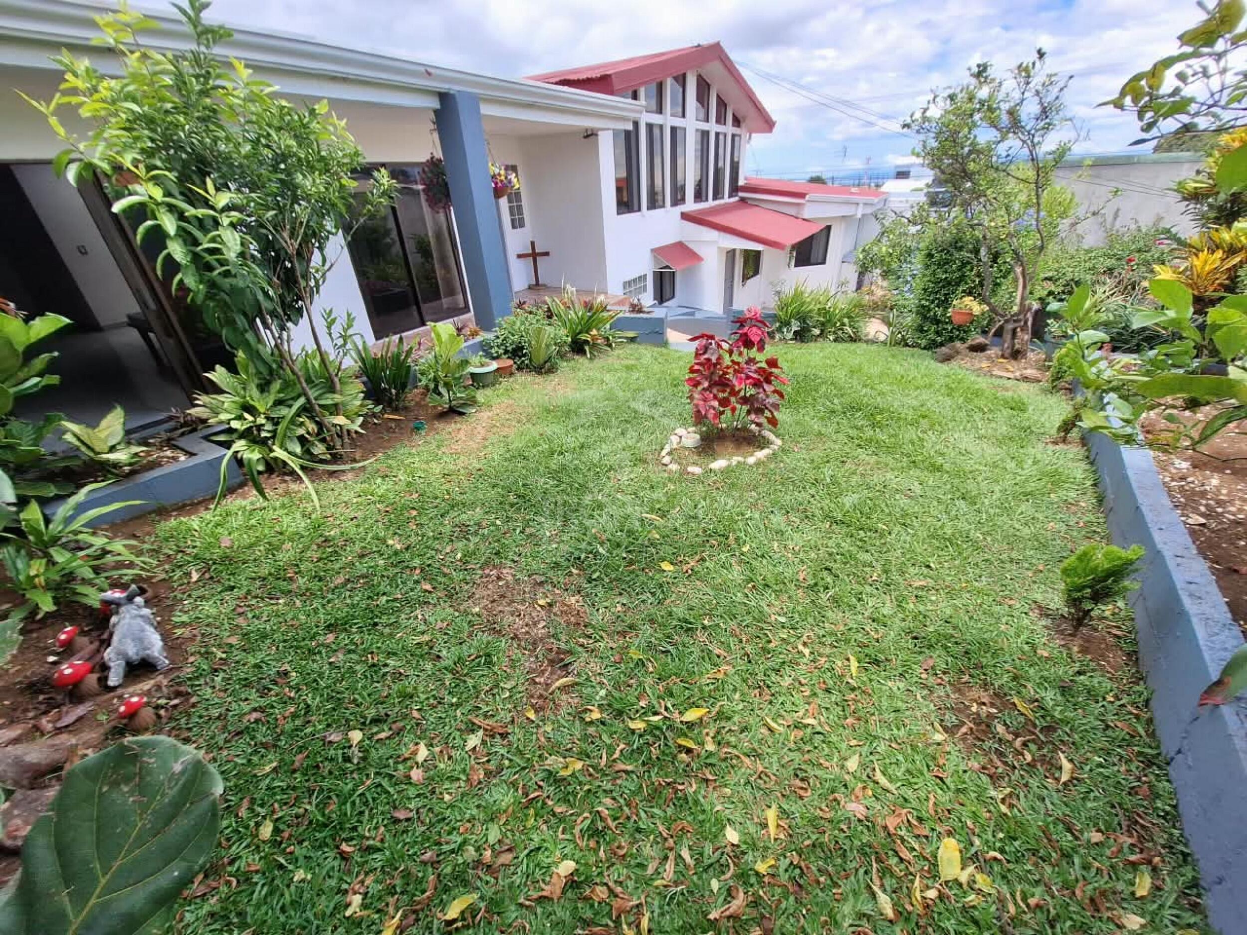 Jardín privado con vegetación tropical y vista a la residencia en Heredia