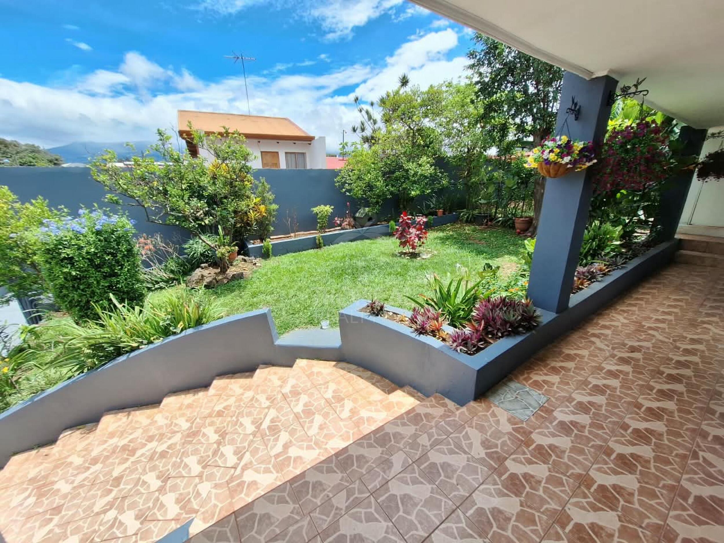 Terraza cubierta junto a un jardín privado con plantas tropicales maduras