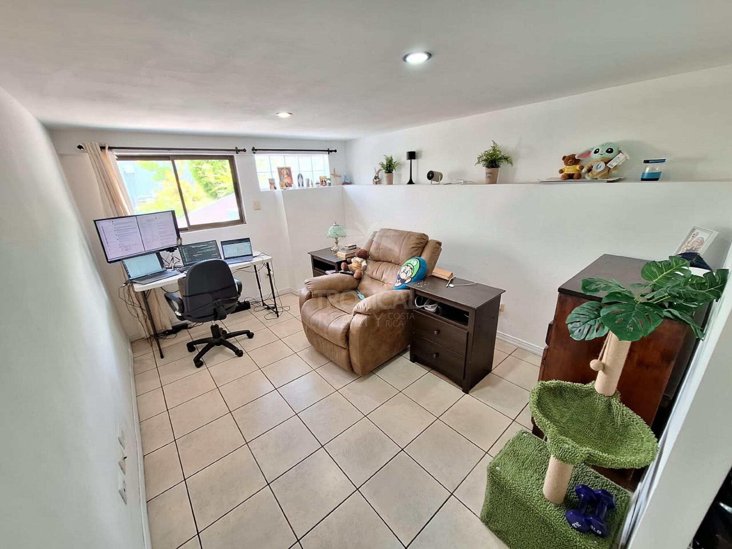 Ambiente con sala y escritorio junto a las ventanas