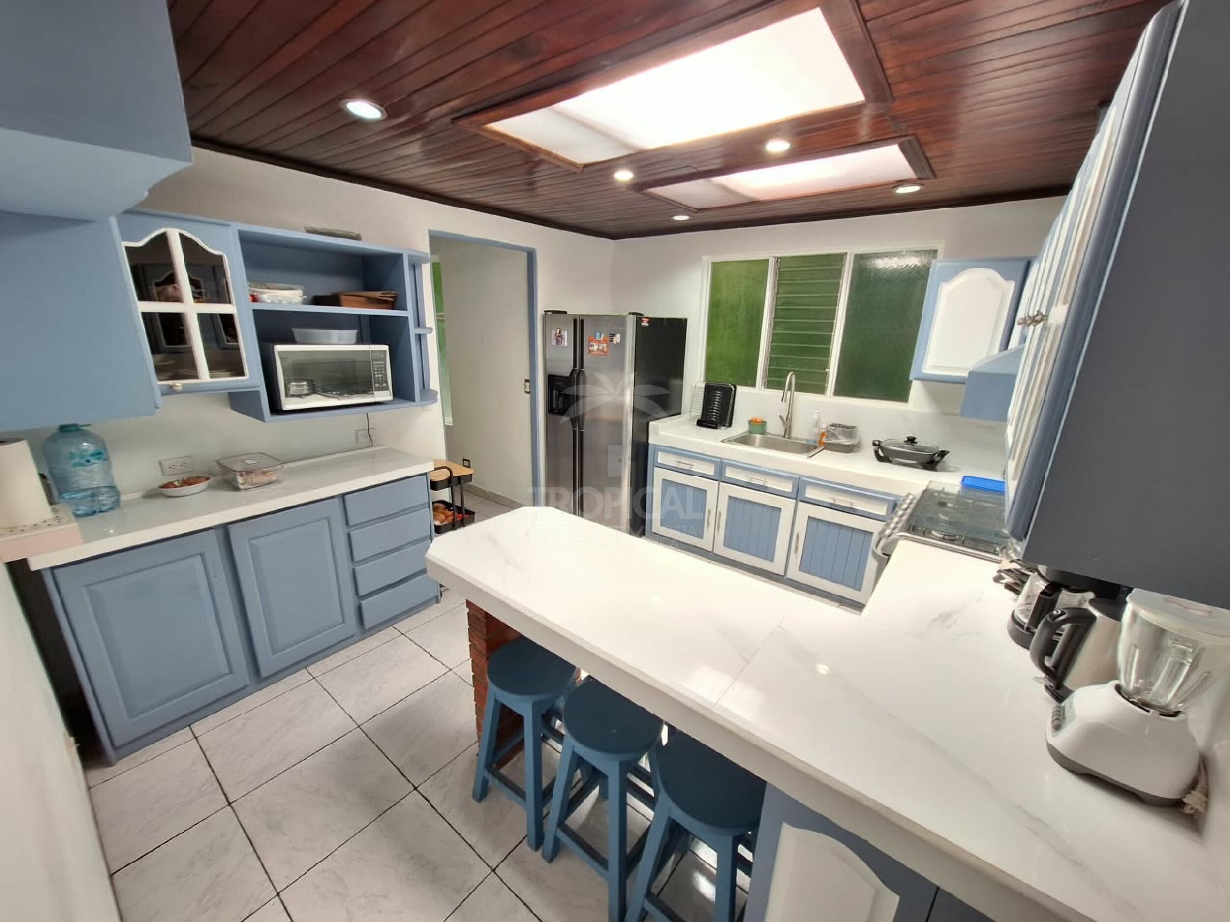 Cocina con barra, cielo de madera oscura y luz natural